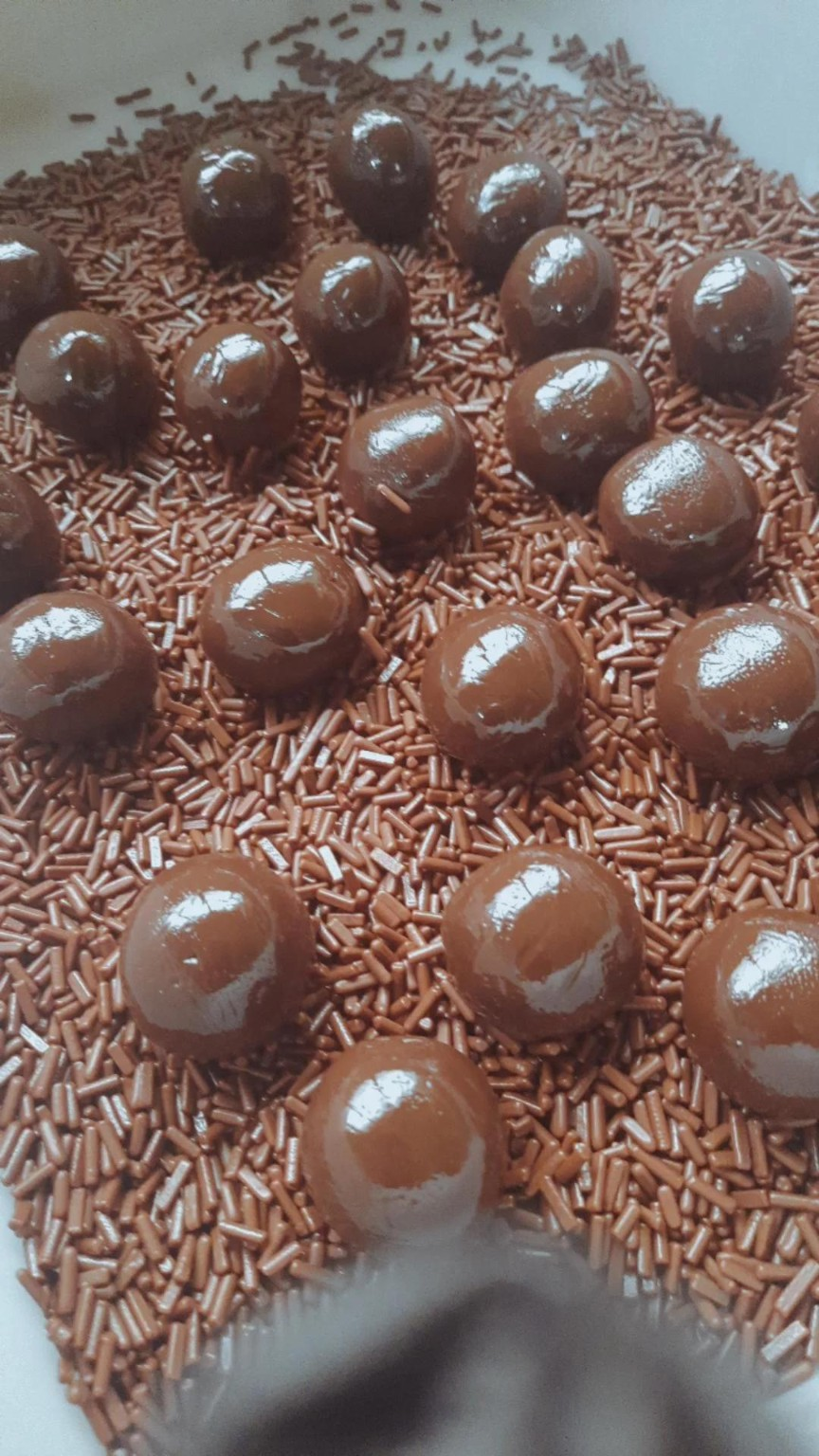 Brigadeiros recebendo acabamento com granulado